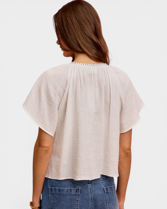 Woman wearing a beige textured top and blue jeans on a white background