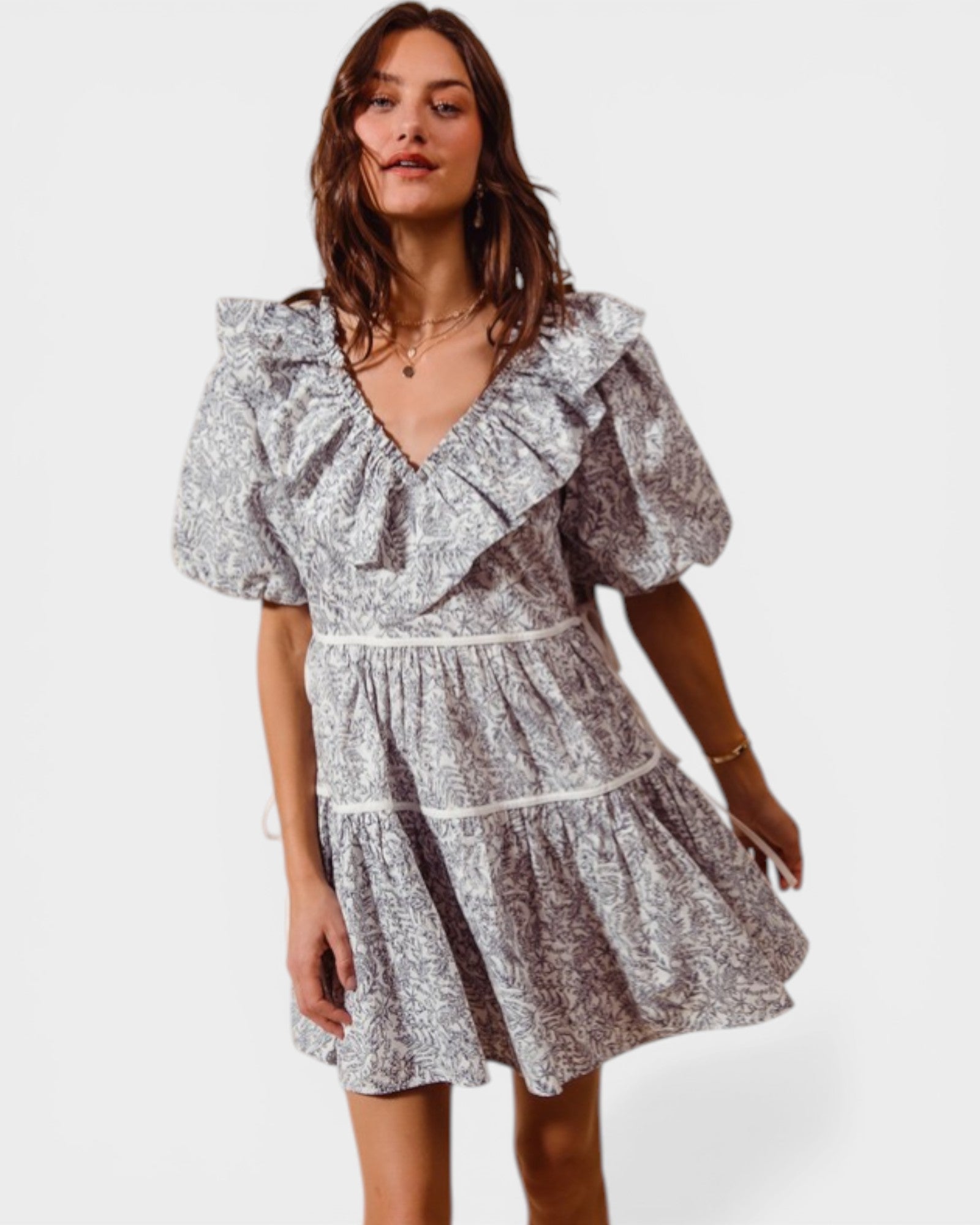 Woman wearing a floral dress with ruffled sleeves on a white background