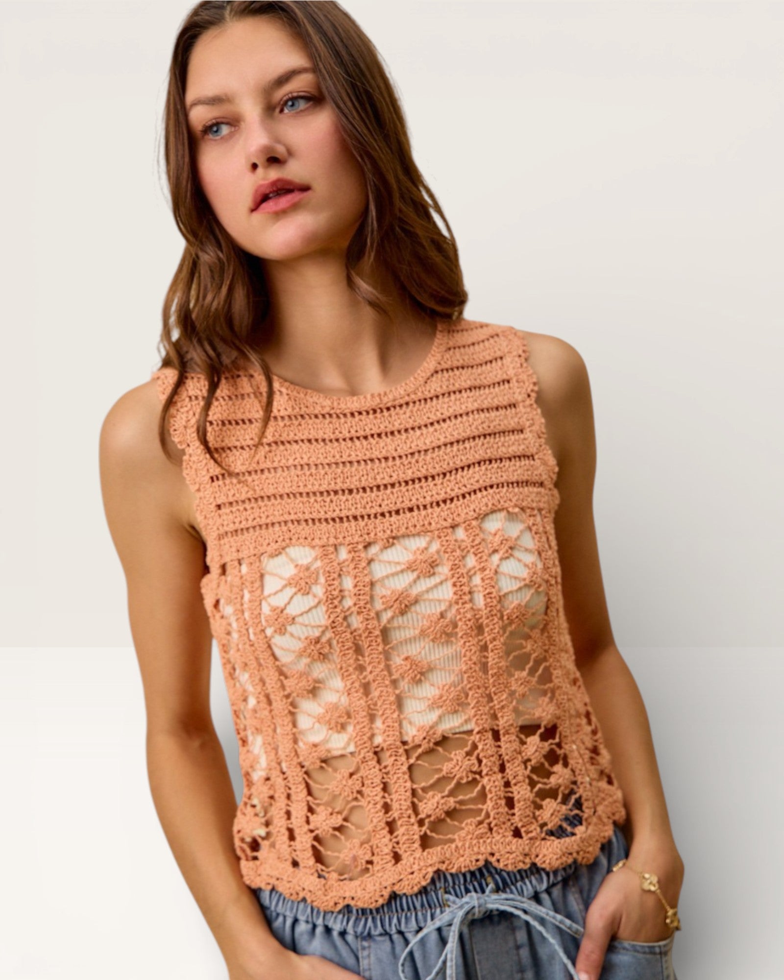 Woman wearing a peach-colored crochet top against a plain background