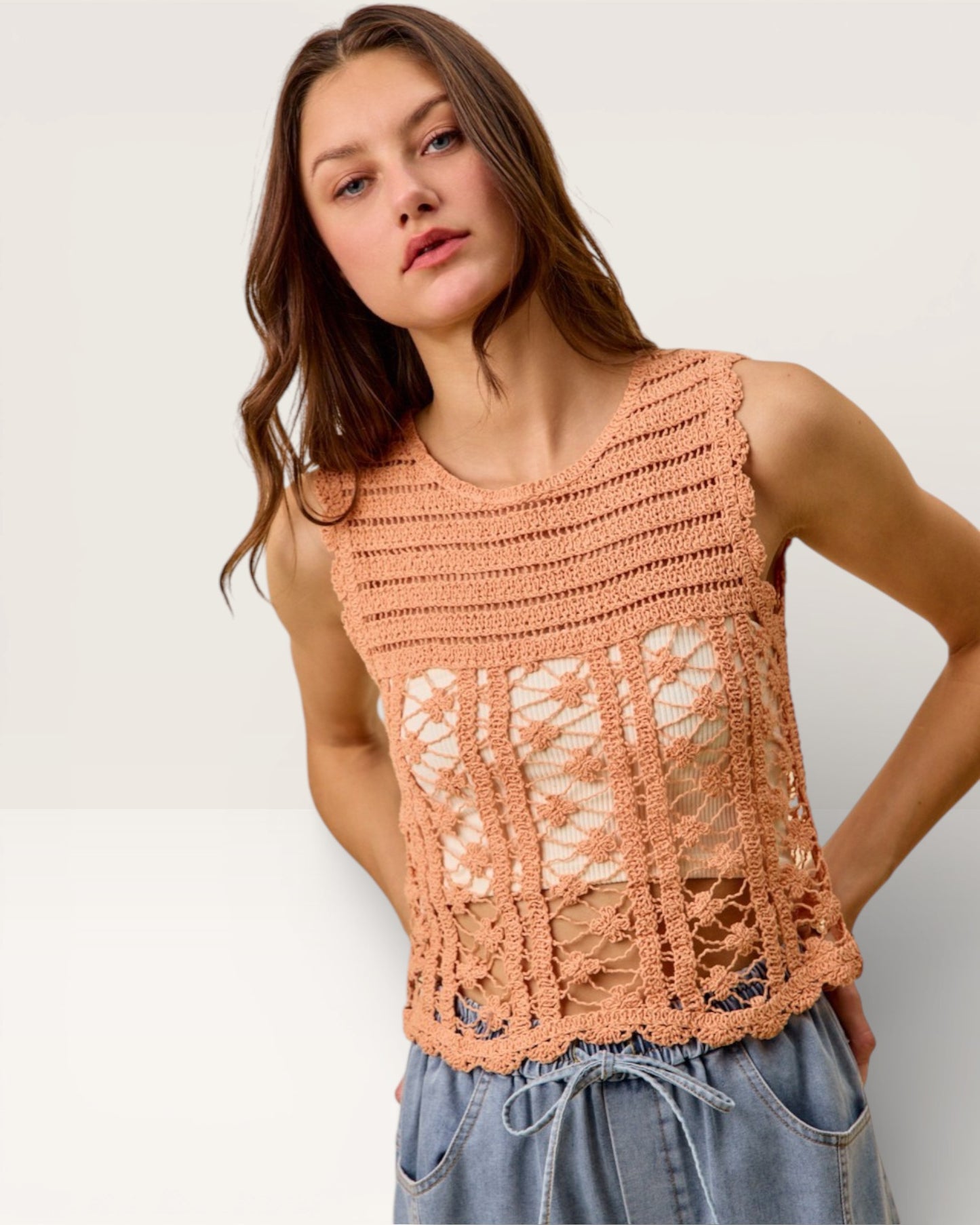 Woman wearing a peach-colored crochet top against a plain background