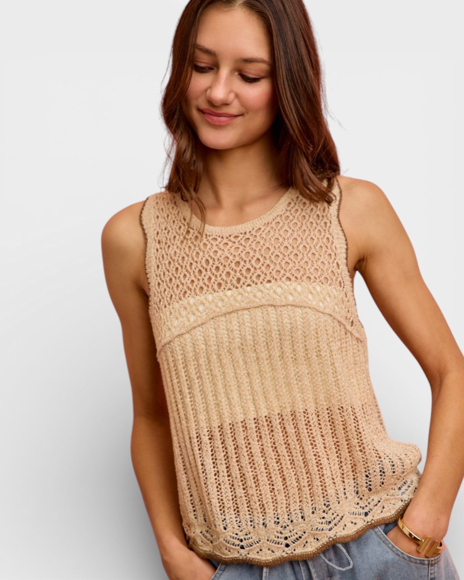 Woman wearing a beige knitted sleeveless top on a white background