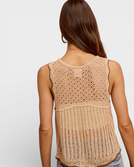 Woman wearing a beige crochet tank top on a plain background