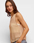 Woman wearing a beige crochet tank top against a plain background