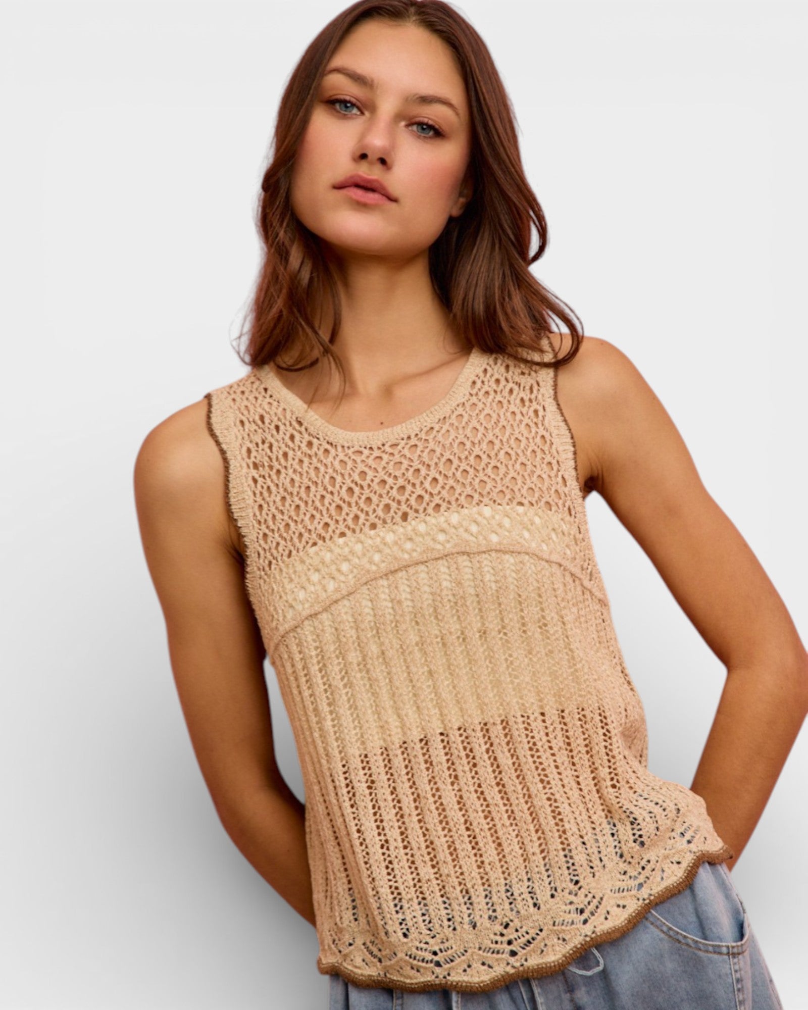 Woman wearing a beige crochet top against a plain background