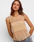 Woman wearing a beige crochet top against a plain background