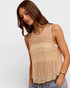 Woman wearing a beige knitted sleeveless top against a plain background