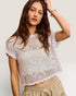 Woman wearing a white lace top against a plain background