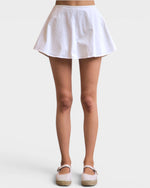 White skirt worn by a person on a plain background