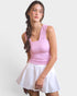 Woman wearing a pink top and white skirt on a plain background