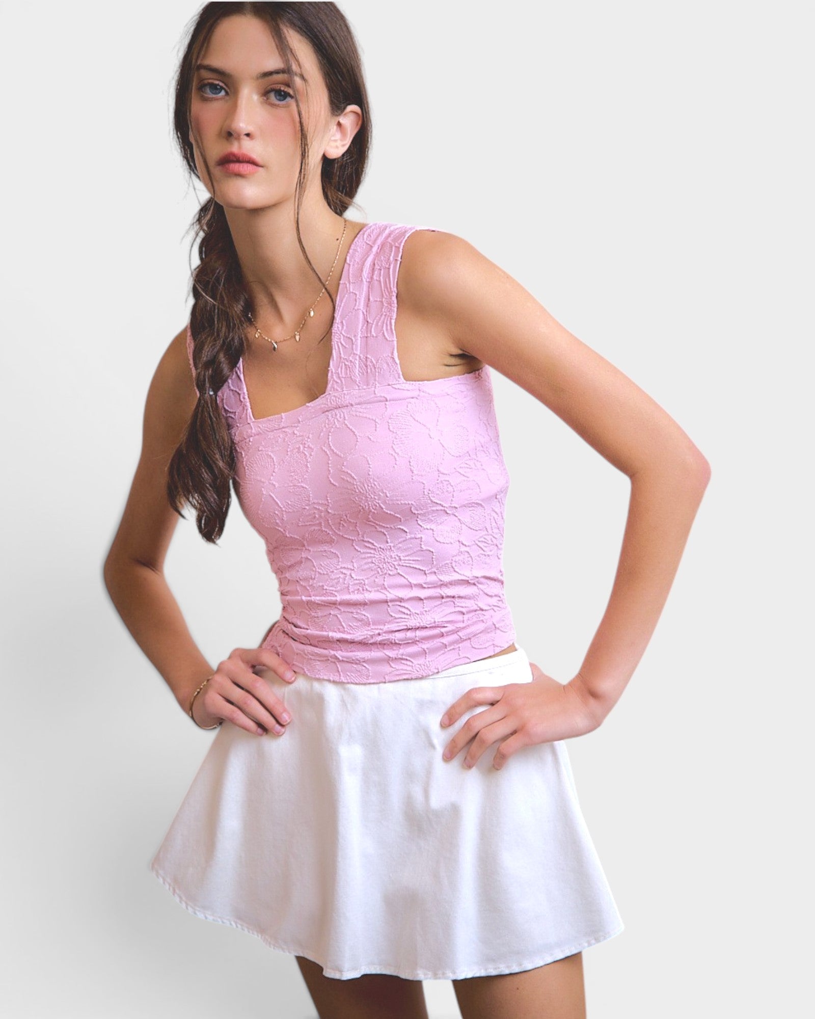 Woman wearing a pink top and white skirt on a plain background
