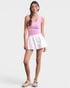 Woman wearing a pink top and white skirt on a plain background