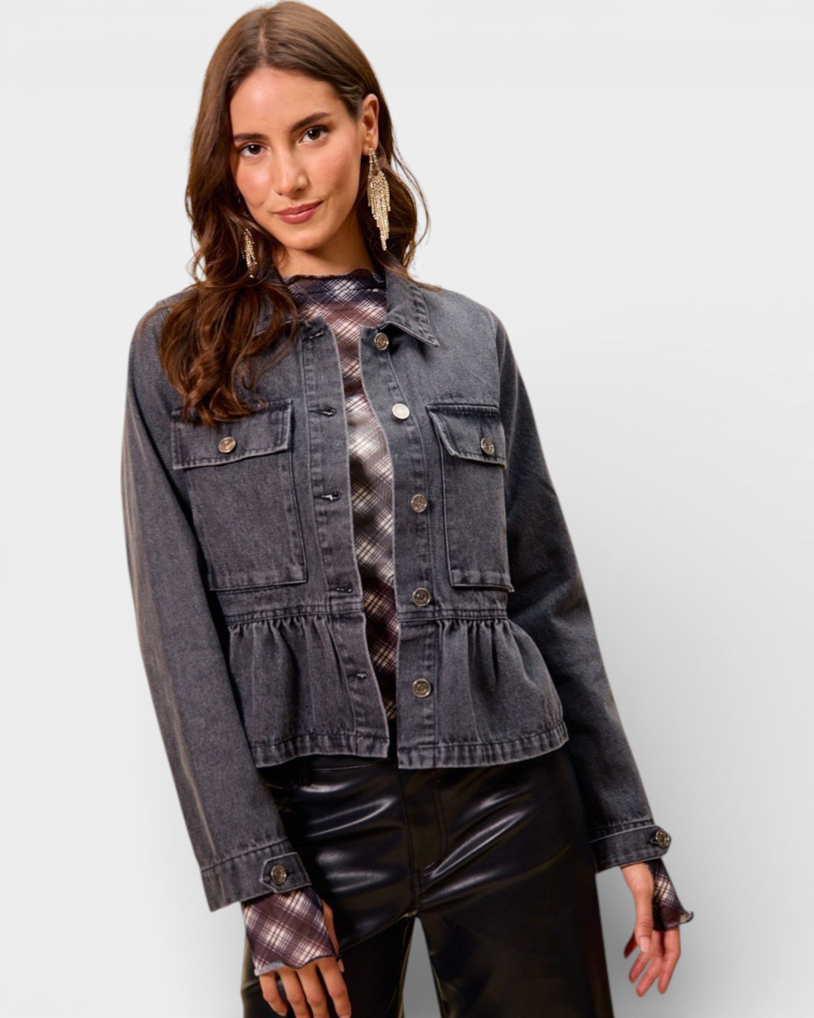 Woman wearing a denim jacket with a plain background