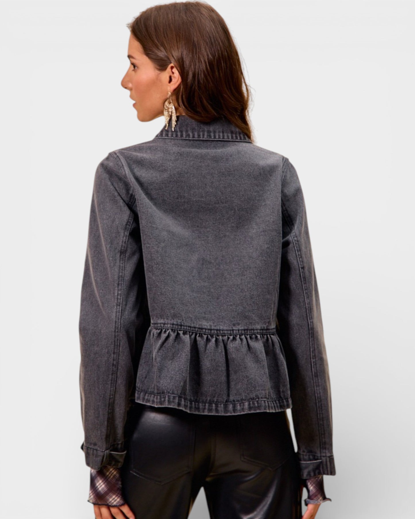 Woman wearing a gray denim jacket with a peplum waist on a light gray background