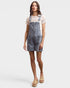 Woman wearing denim overalls over a lace top on a plain background