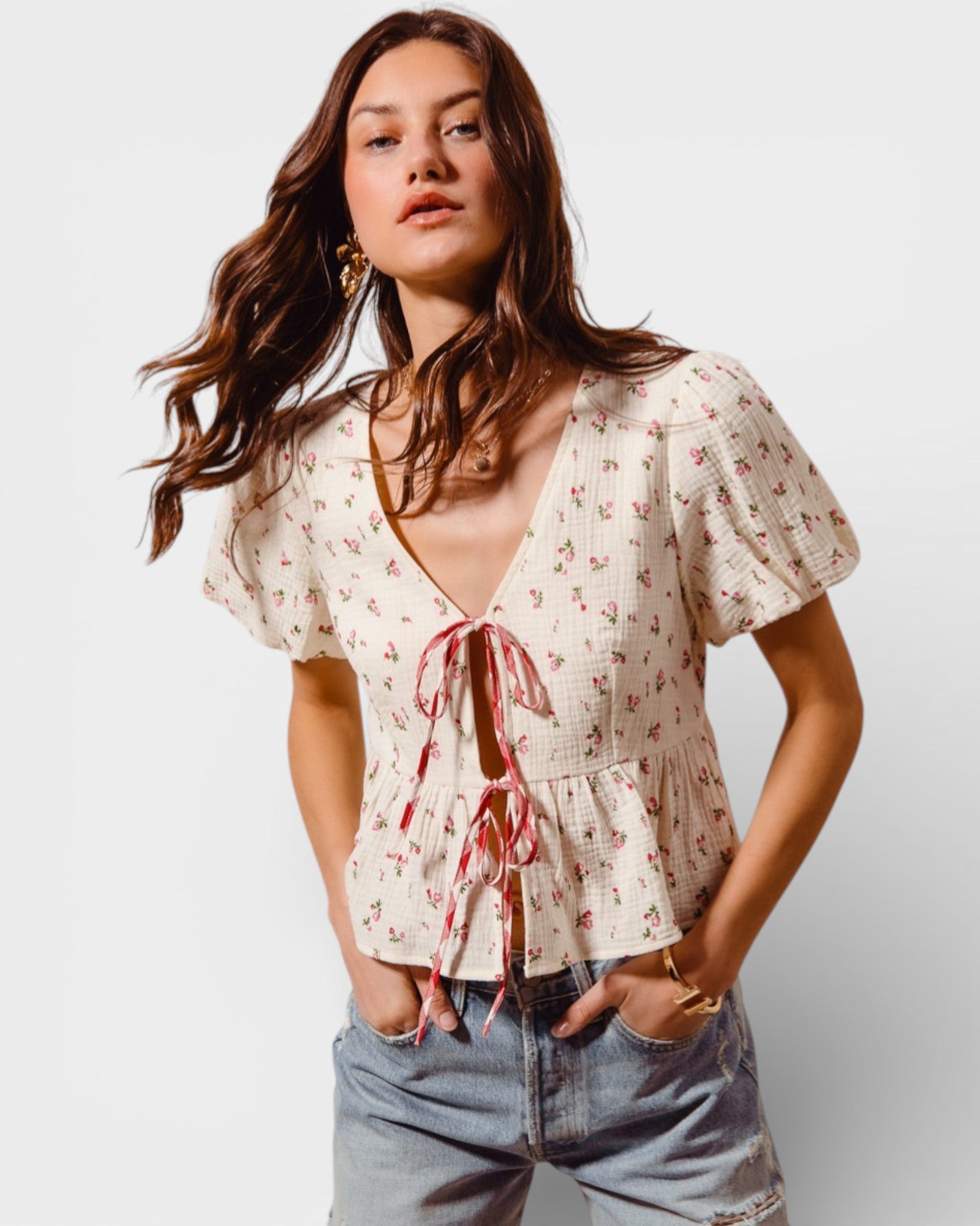 Woman wearing a floral blouse with a tie detail on a plain background