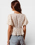 Woman wearing a floral blouse and jeans on a plain background