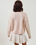 Person wearing a light pink sweater and white skirt on a plain background
