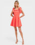 Woman wearing a coral dress with bow straps on a white background