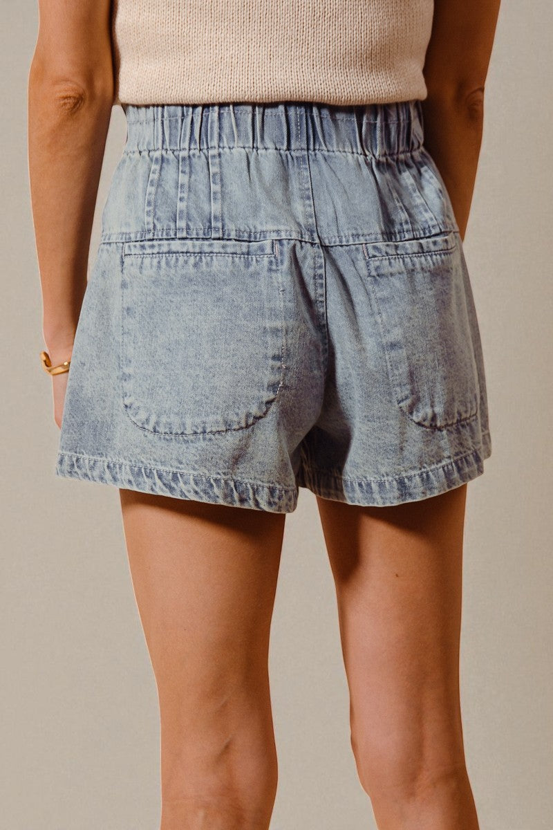 Light blue denim shorts worn by a person on a beige background