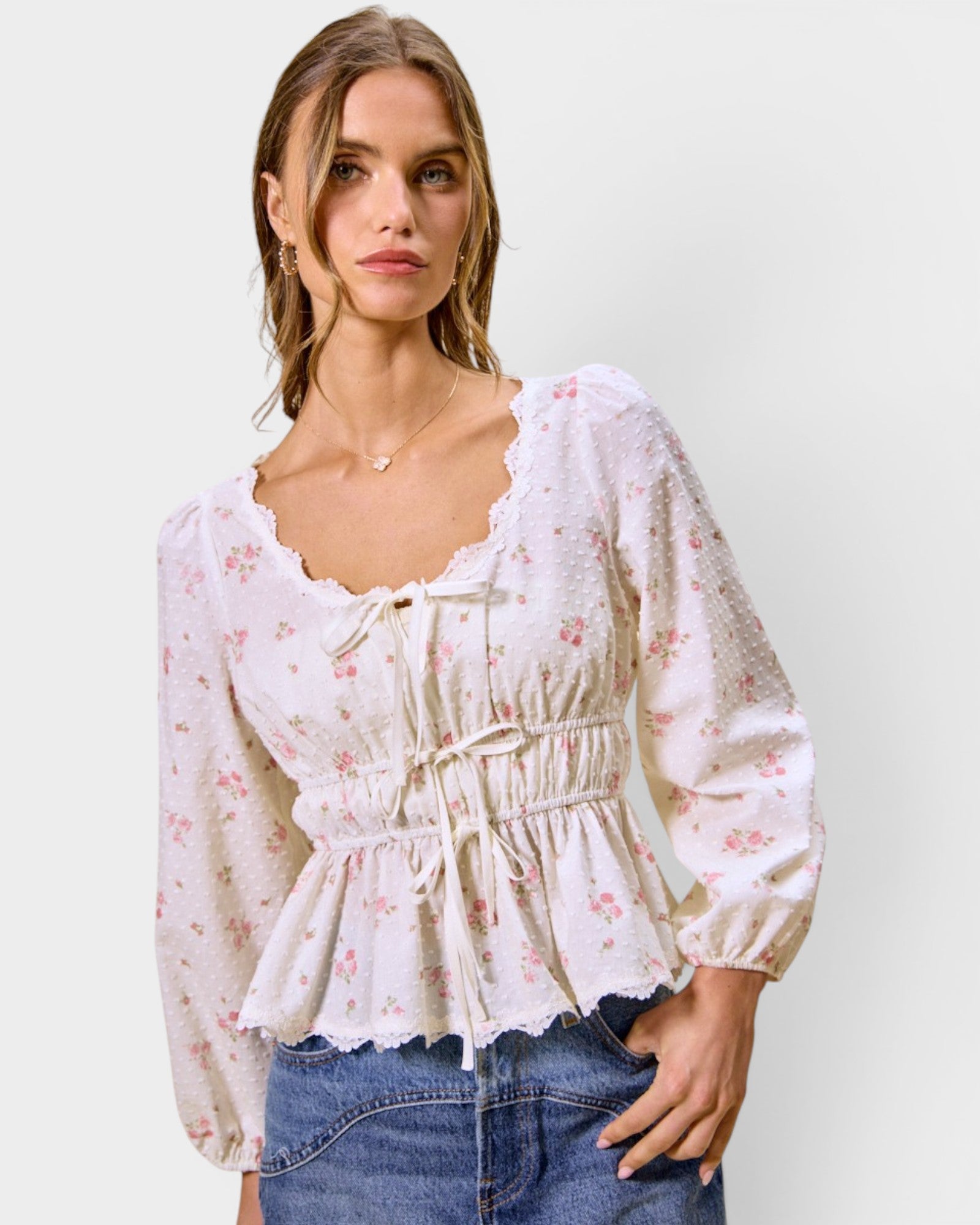 Woman wearing a floral blouse and jeans on a plain background