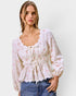 Woman wearing a floral blouse and jeans on a plain background