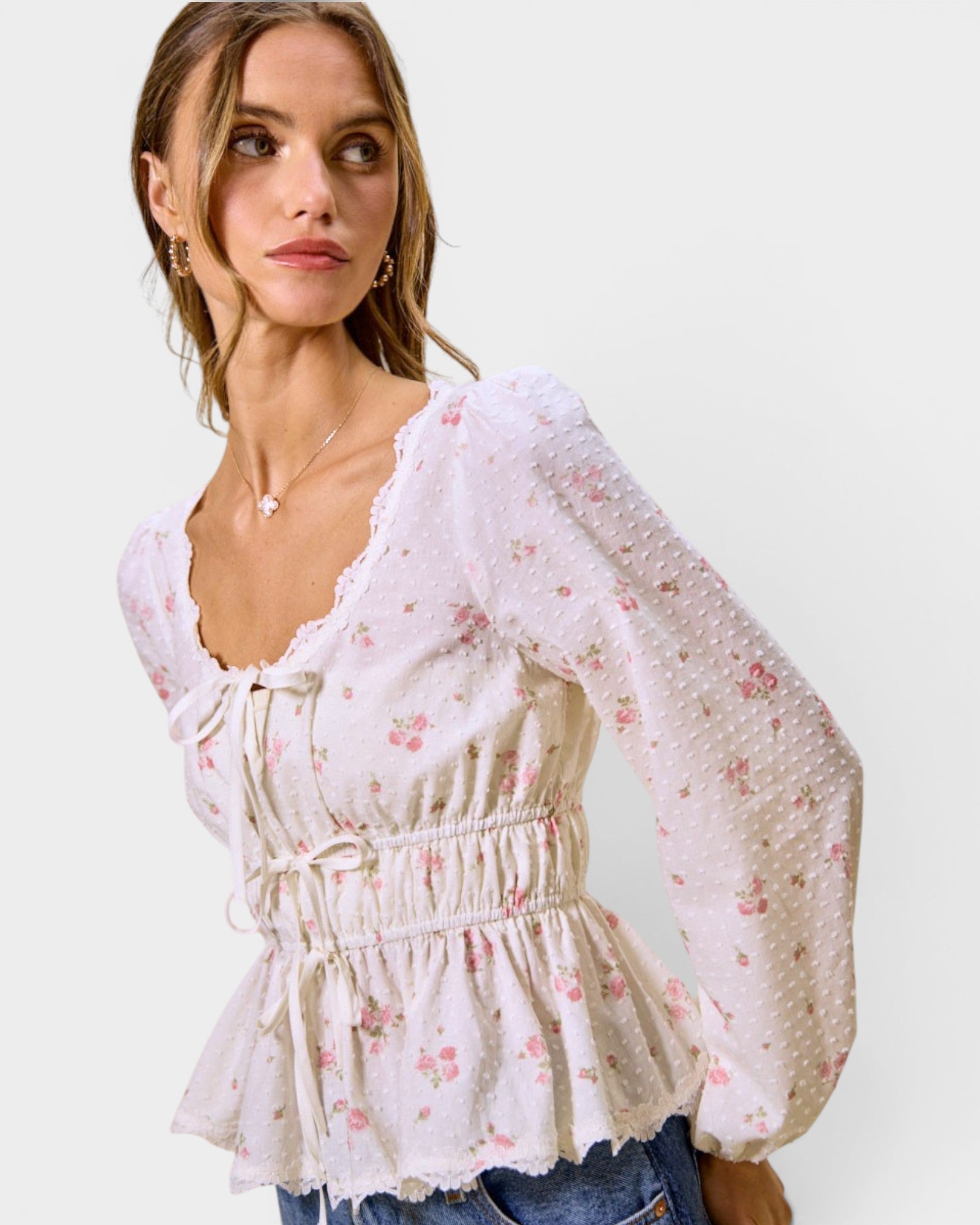 Woman wearing a floral blouse with sheer sleeves on a white background