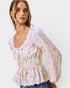 Woman wearing a floral blouse with sheer sleeves on a white background