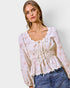 Woman wearing a floral blouse and jeans against a plain background