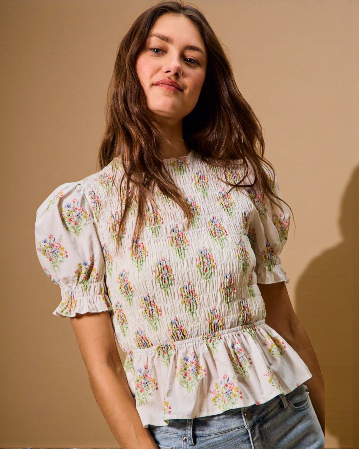 Woman wearing a floral blouse against a beige background
