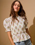 Woman wearing a floral blouse against a beige background