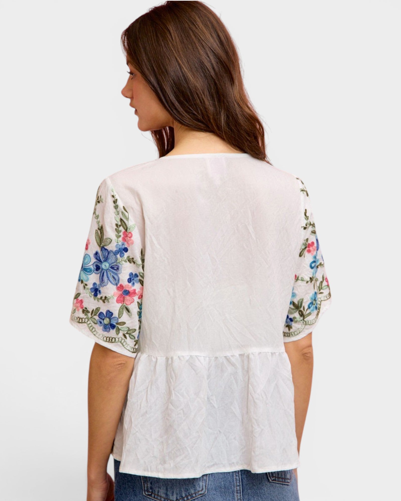 Woman wearing a white blouse with floral sleeves on a white background