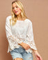 Woman wearing a white lace top and denim shorts on a beige background