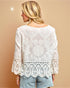 Woman wearing a white lace top against a beige background