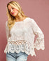 Woman wearing a white lace top against a pink background