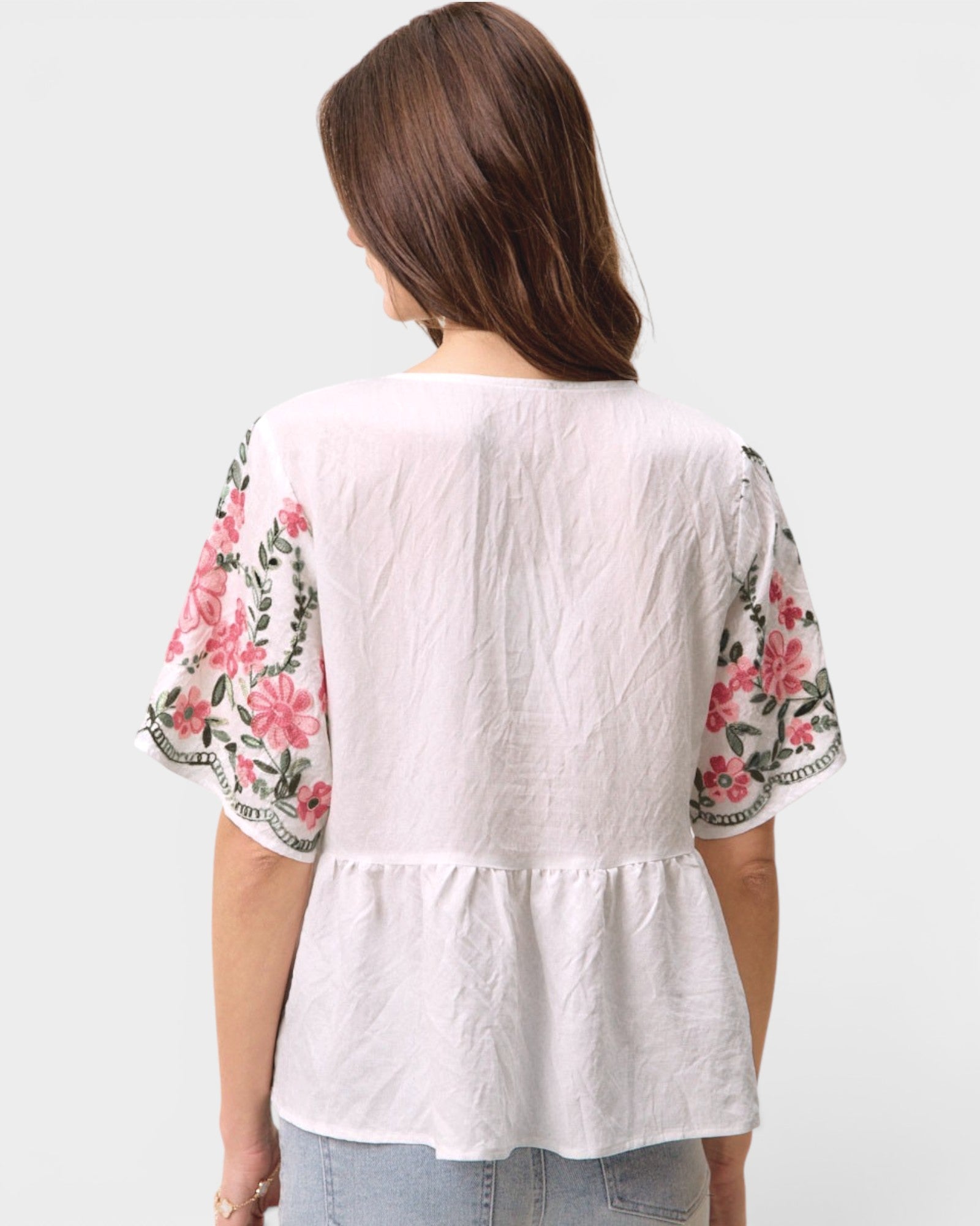 White blouse with floral sleeves on a plain background
