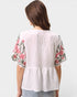 White blouse with floral sleeves on a plain background