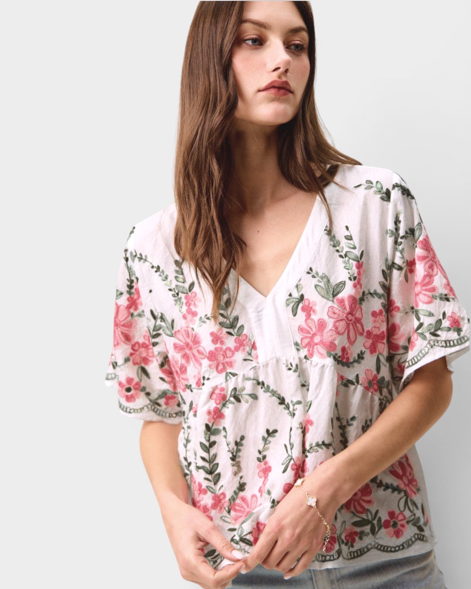 Woman wearing a floral blouse with pink flowers on a plain background