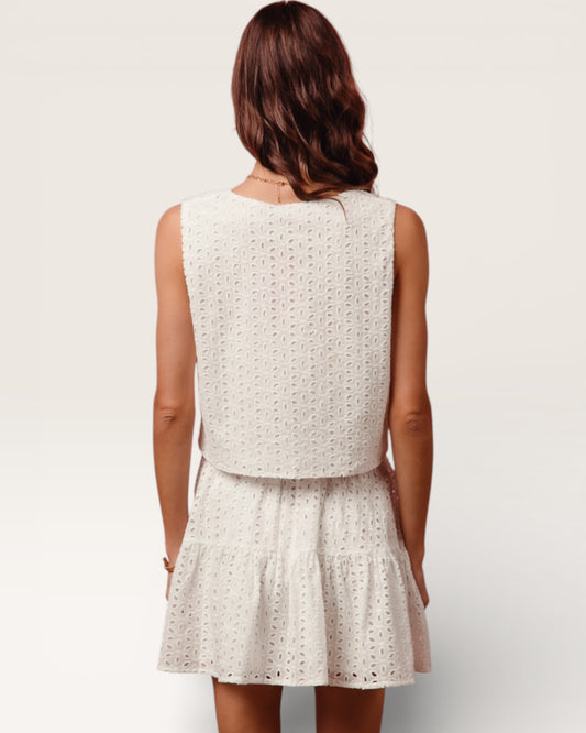 Woman wearing a white sleeveless dress with a subtle pattern on a plain background