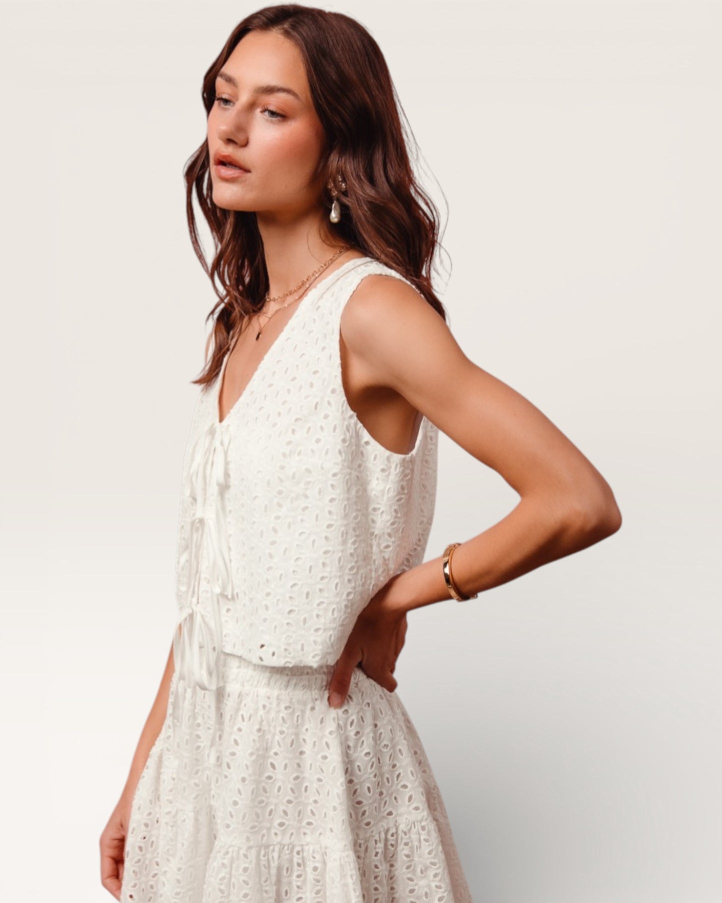 Woman wearing a white sleeveless dress against a plain background