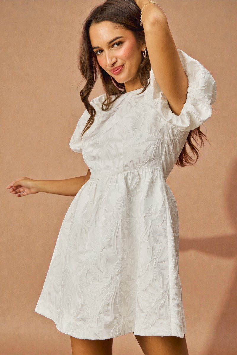 Woman wearing a white dress against a beige background