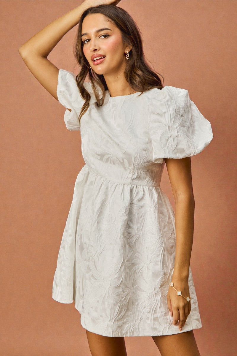 Woman wearing a white dress with puffed sleeves against a brown background