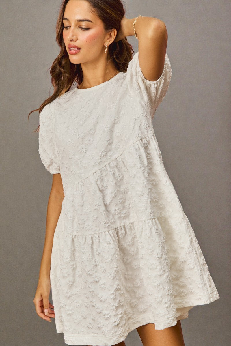 Woman wearing a light gray dress against a plain background