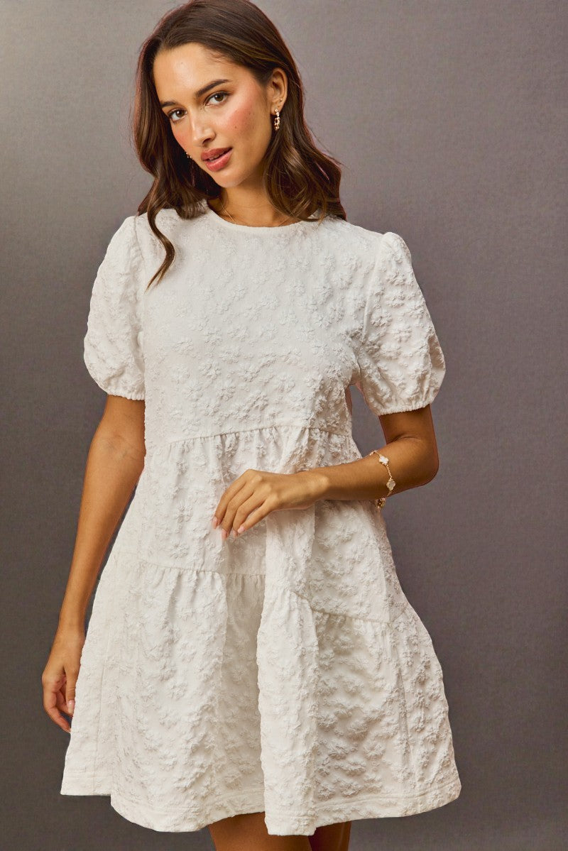 Woman wearing a light gray dress with puff sleeves against a gray background