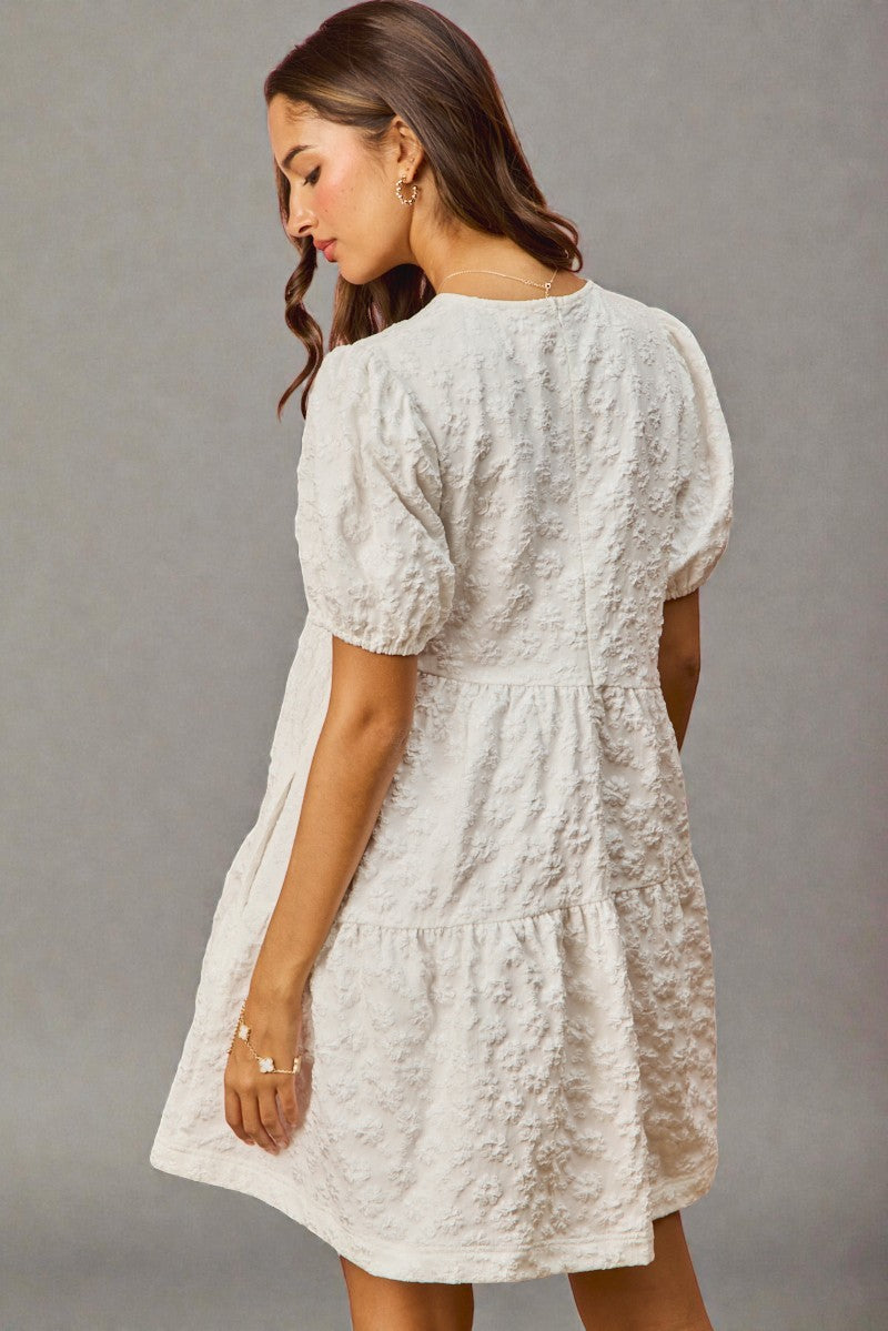 Woman wearing a white lace dress against a gray background