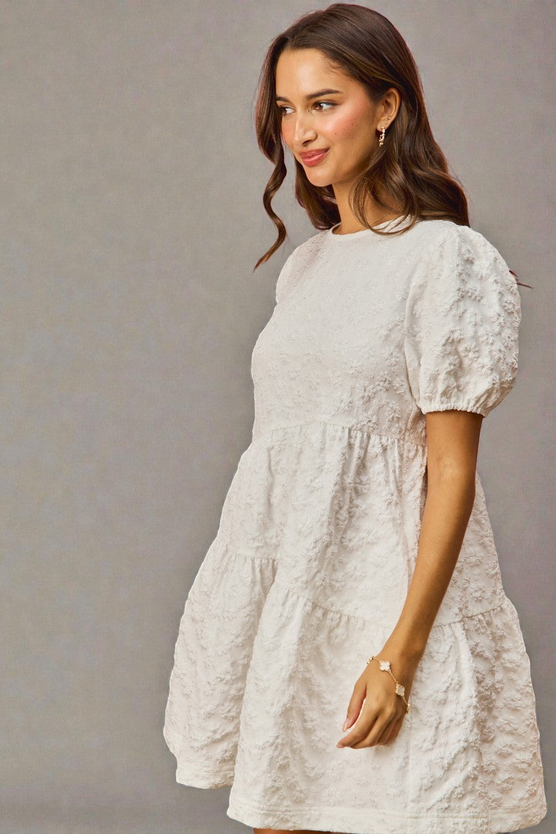 Woman wearing a white lace dress against a gray background