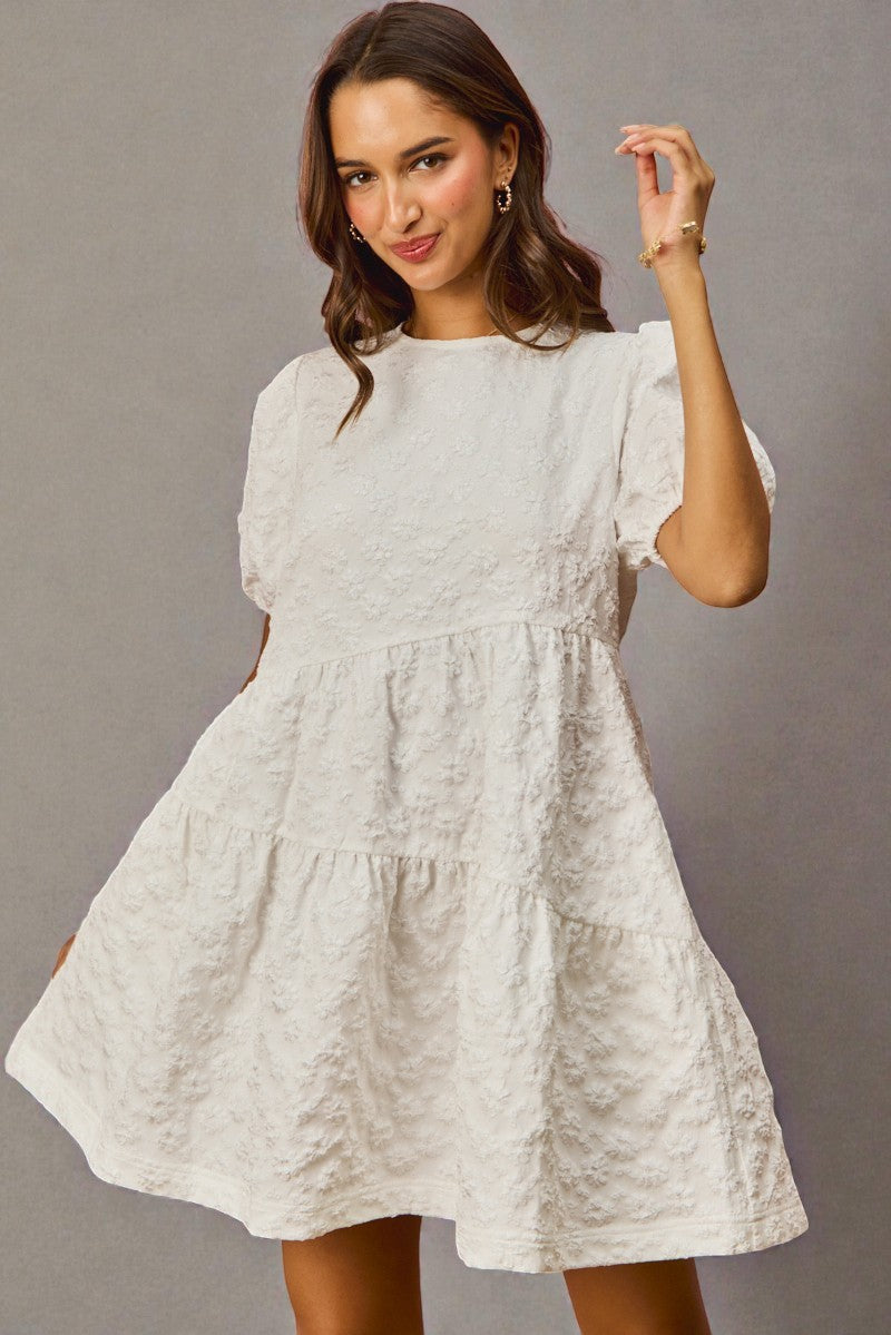 Woman wearing a white lace dress against a gray background