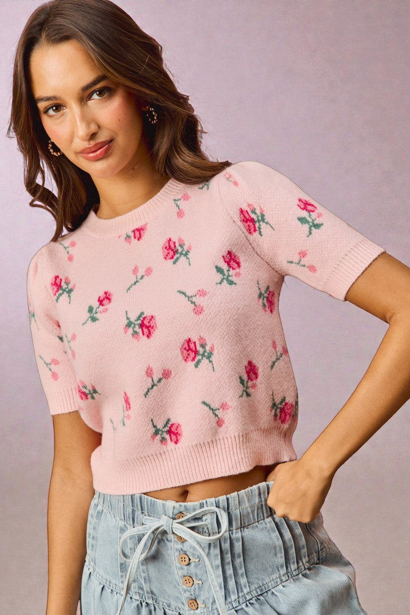 Woman wearing a pink floral sweater against a plain background
