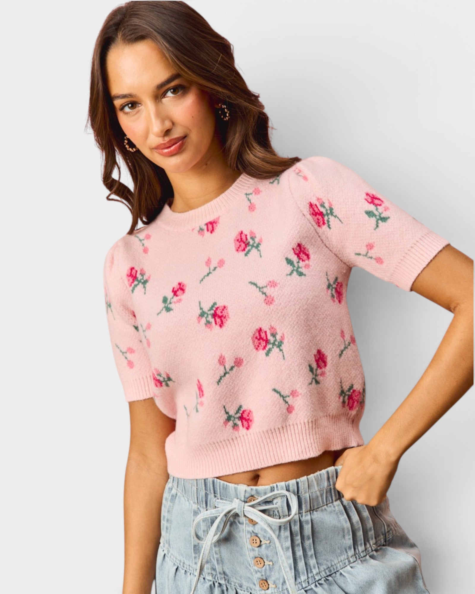 Woman wearing a pink floral sweater against a plain background