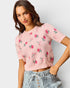 Woman wearing a pink floral sweater against a plain background