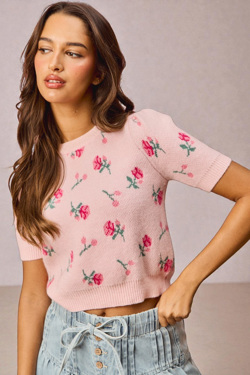 Woman wearing a pink floral sweater against a neutral background